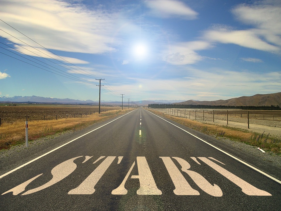 Image of a paved straight road with the word START painted on it. There is a blue sky and mountains in the background.