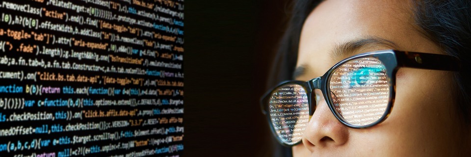 Image of a woman of Asian descent who is looking at a screen, which is then reflected in her glasses, to demonstrate the idea of reflection.