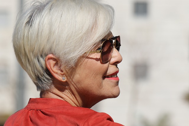 Image of a middle-aged white woman with white hair, looking at her from the back and she is slightly looking back