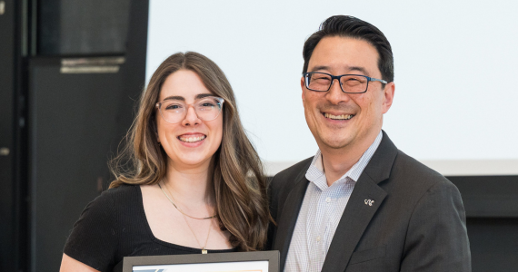 student posing with award certificate and staff member