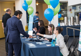 main in suit checking in at registration table with navy linen and balloons