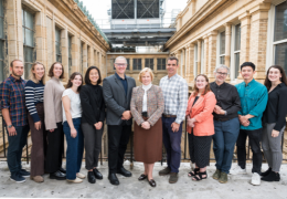 Group of Graduate College Doctoral Fellows and faculty standing on landing on third floor of Main Building