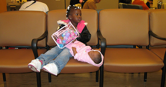 Girl with doll sitting in doctor's office waiting room