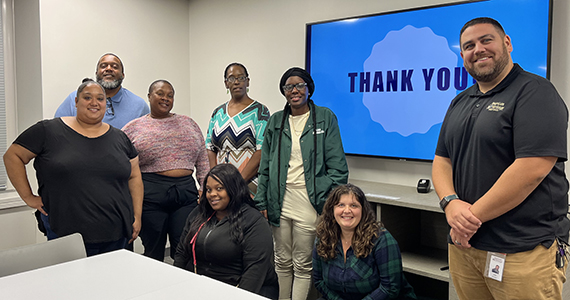 Group of adults smiling in front of screen that says thank you