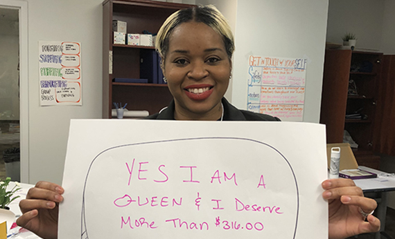 Woman holding sign that says: Yes I am a Queen and I deserve more than $316