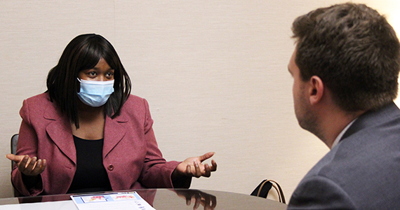 Woman in pink blazer talking to man