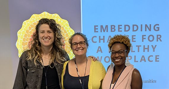 Three women smiling in front of a presentation screen