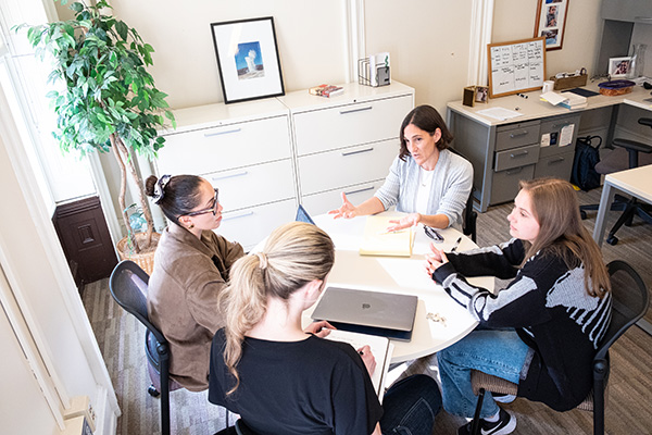 Professor Katz Smith speaks with three students at a table in her office.