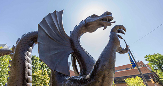 Dragon statue on campus with the sun shining from behind