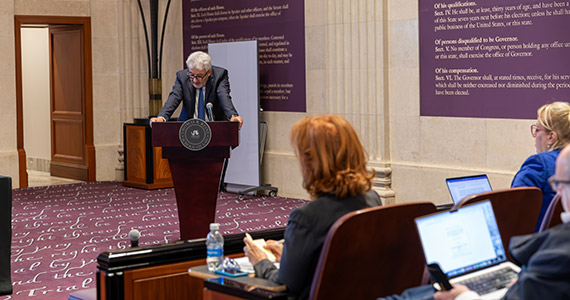 Professor speaks at podium during symposium.