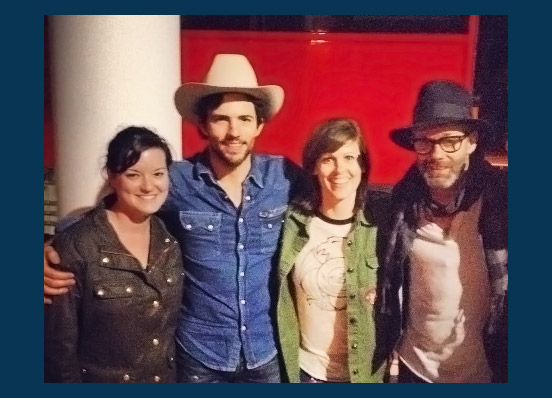 Adria, left, poses with her business partner, Sari Casper, and members of the Avett Brothers band