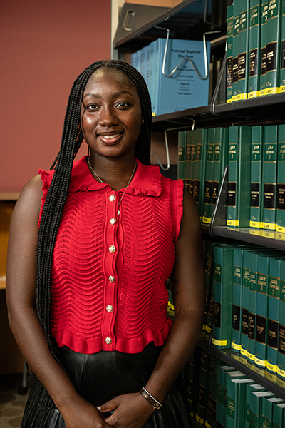Deaven Ross poses for a photo next to a book shelf in the Legal Research Center.