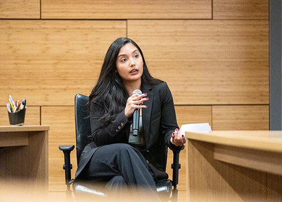 Woman with microphone addresses panelists.