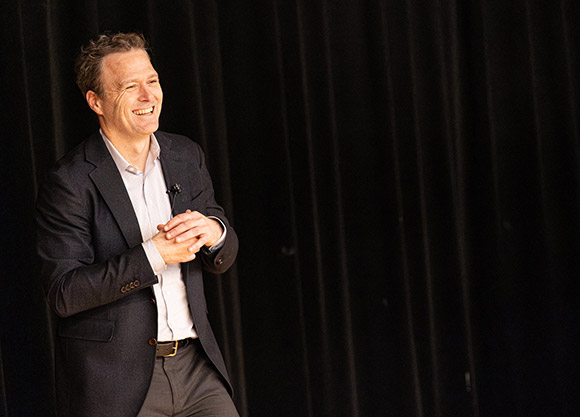 Professor Nicholas Bagley stands on stage while giving a lecture.