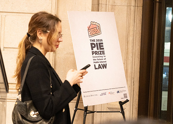 Woman holds phone next to a sign that says "PIE Prize."