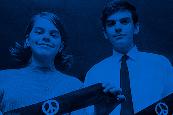 Two students hold black arm bands with peace signs.