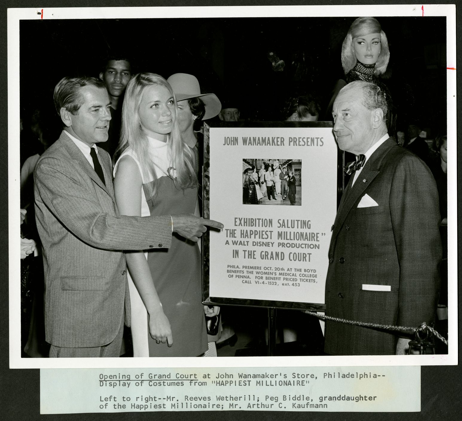 Black and white photograph of 2 men and a woman around 'Happiest Millionaire' poster at the John Wanamaker Store in Philadelphia, 1967 (The Legacy Center Archives and Special Collections)