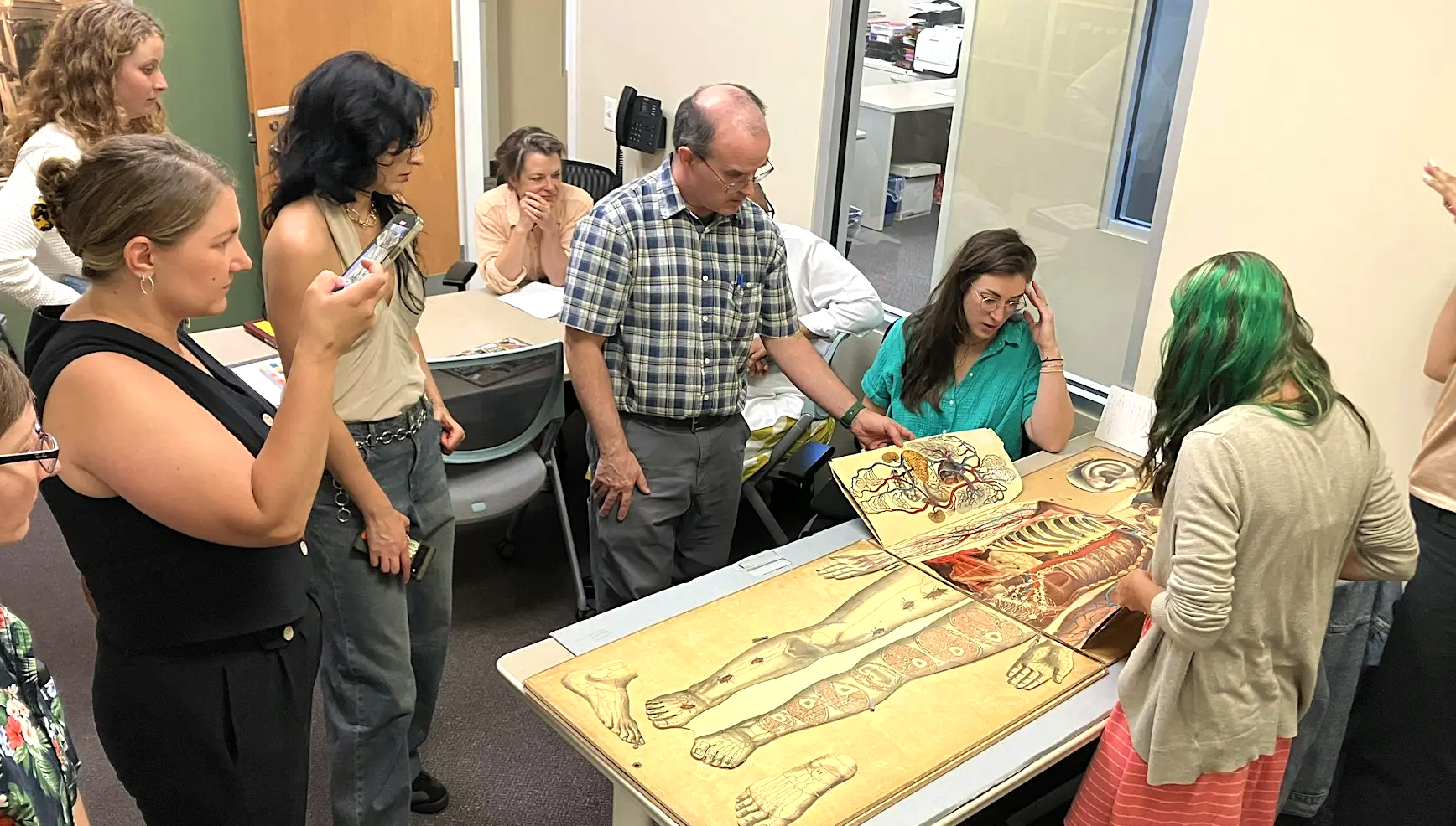 People in the Legacy Center reading room observing a large anatomy manikin (The Legacy Center Archives and Special Collections).