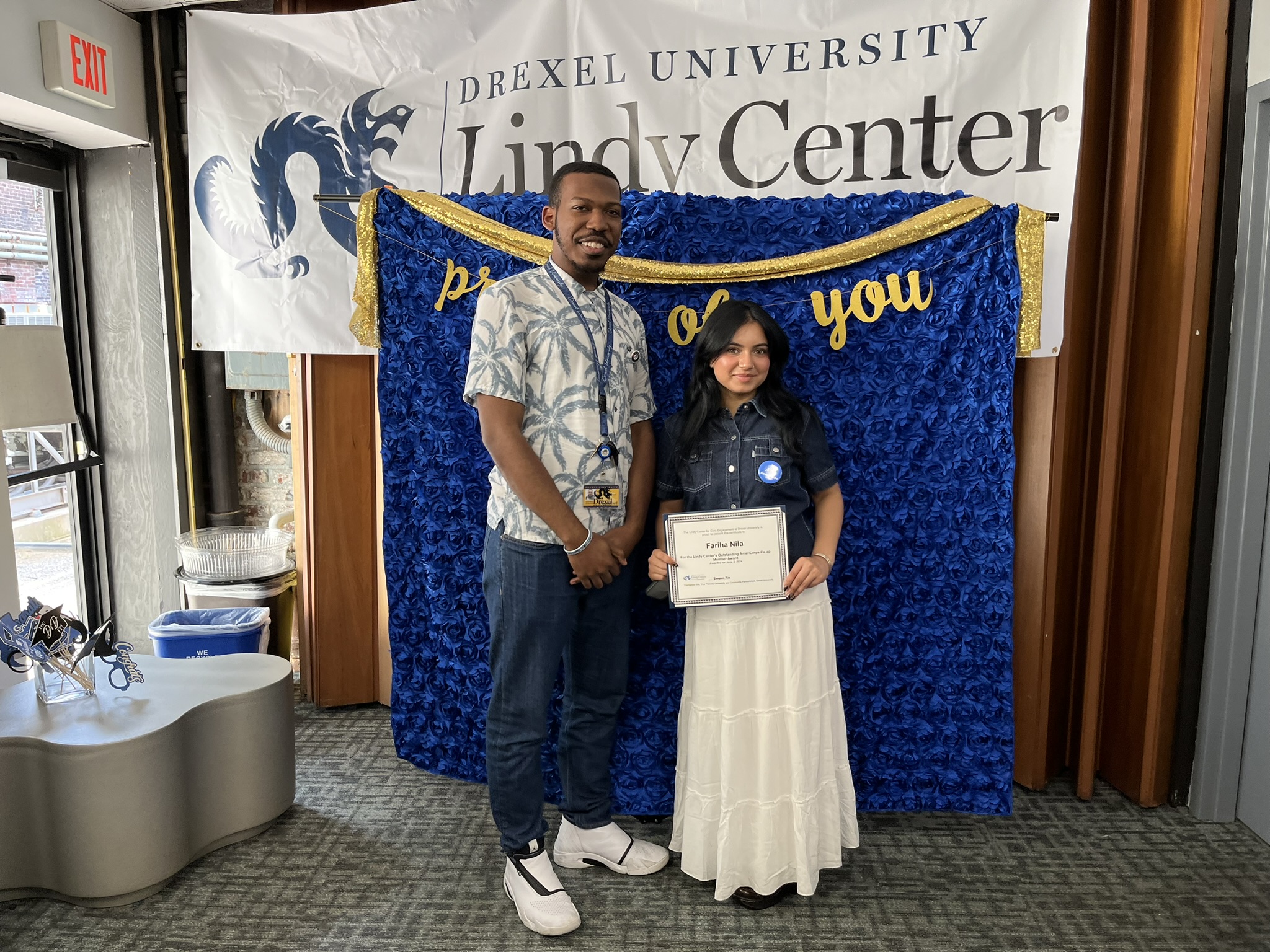 Student receiving an award with a backdrop of the lindy center logo
