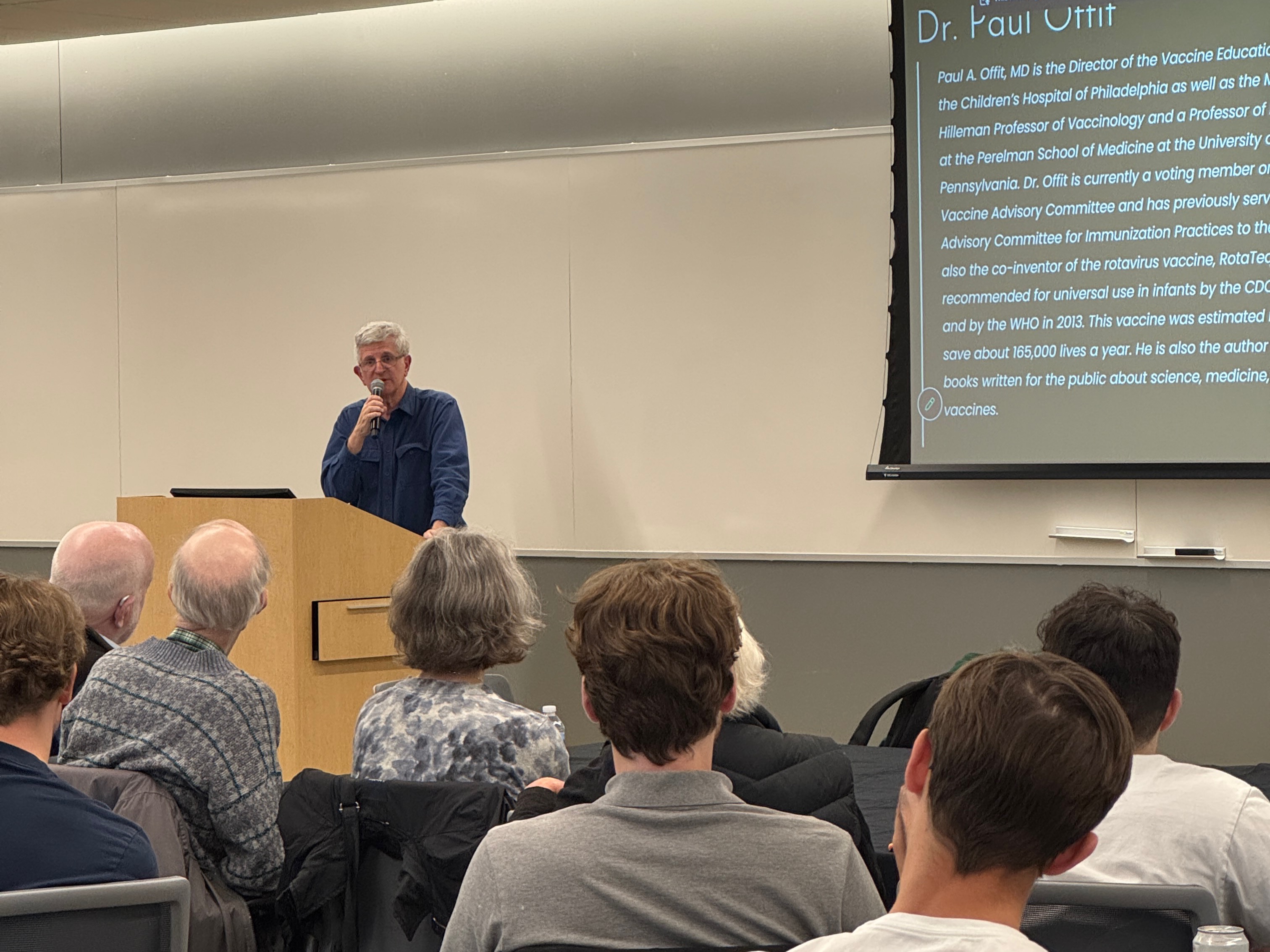 man speaks from behind podium while audience listens