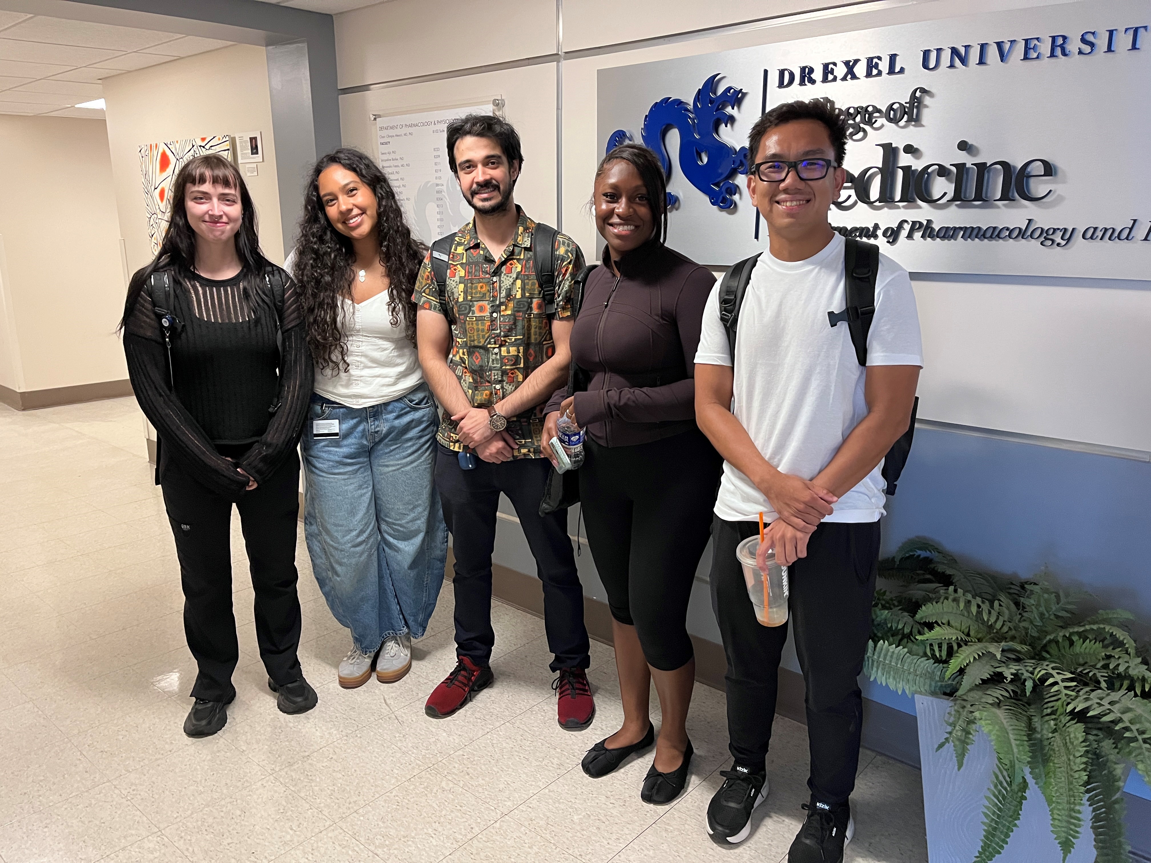 5 students stand in front of the College of Medicine sign smiling