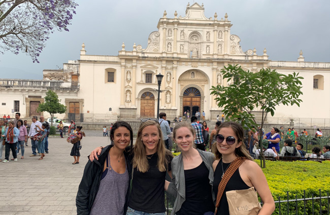 Medical student Ayman Bodair standing with friends in front of a landmark during her Global Health experience with Pop Wuj in Guatemala