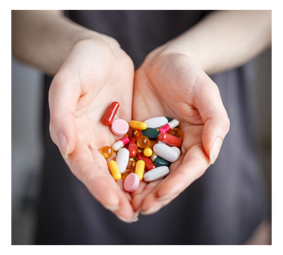 Female holds pills of different color in hand.