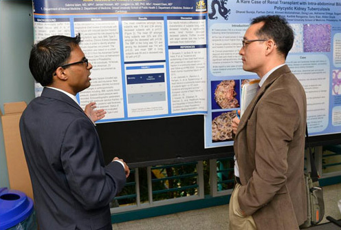 A Drexel graduate student explaining his research poster at Discovery Day.