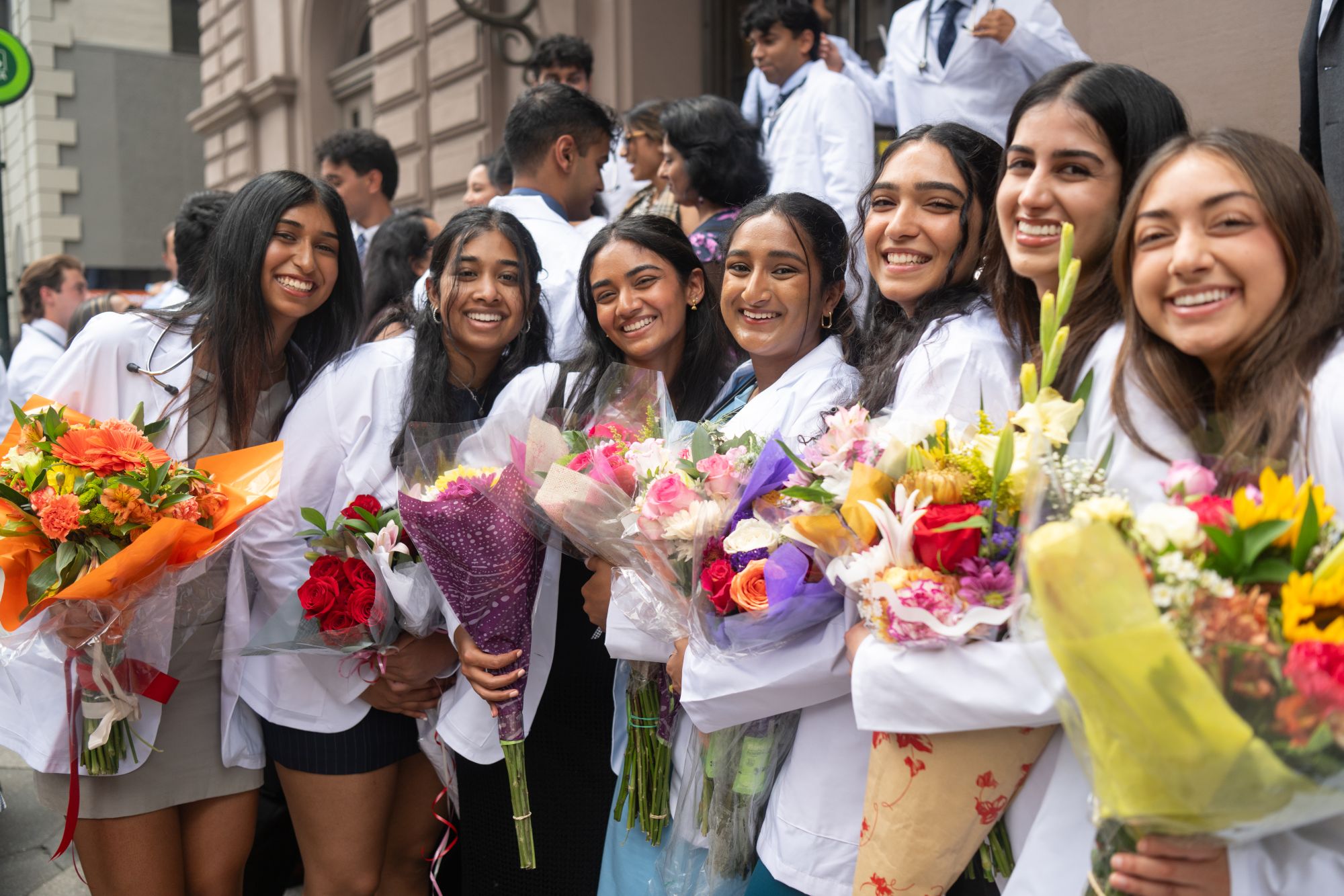 Drexel medical students holding flowers after the White Coat Ceremony