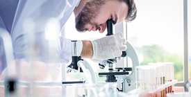 Clinical researcher looking in microscope.