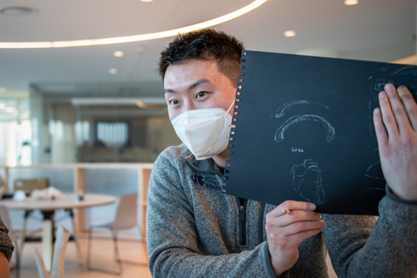 Student wearing a mask holding a drawing made during the Dispassionate Observation event