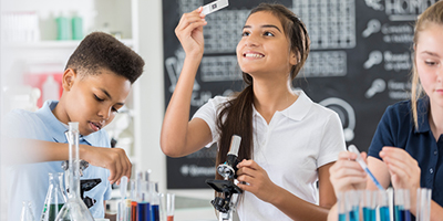 Middle school student examines microscope slide.