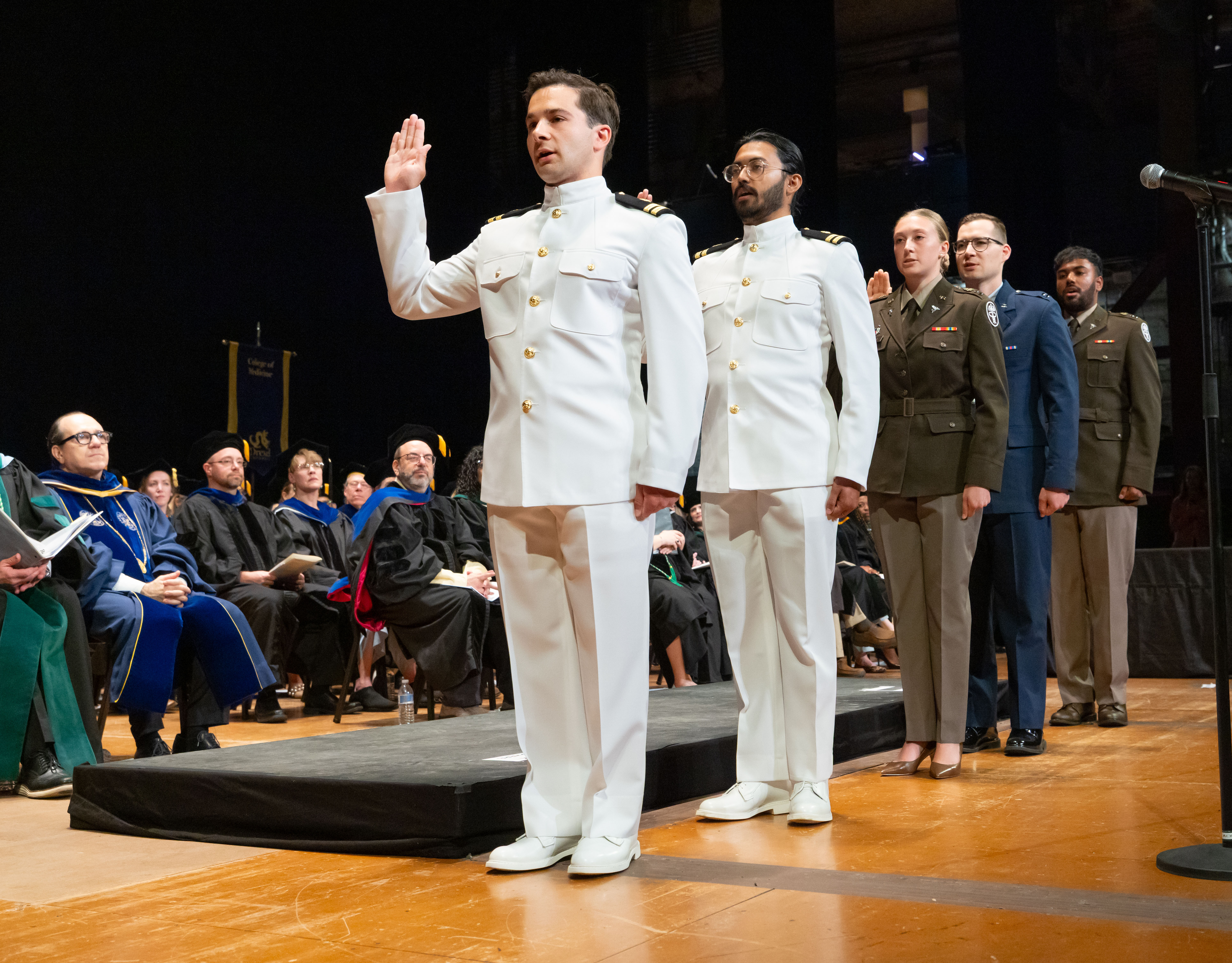 row of 5 military personnel in various uniforms raising arm in oath