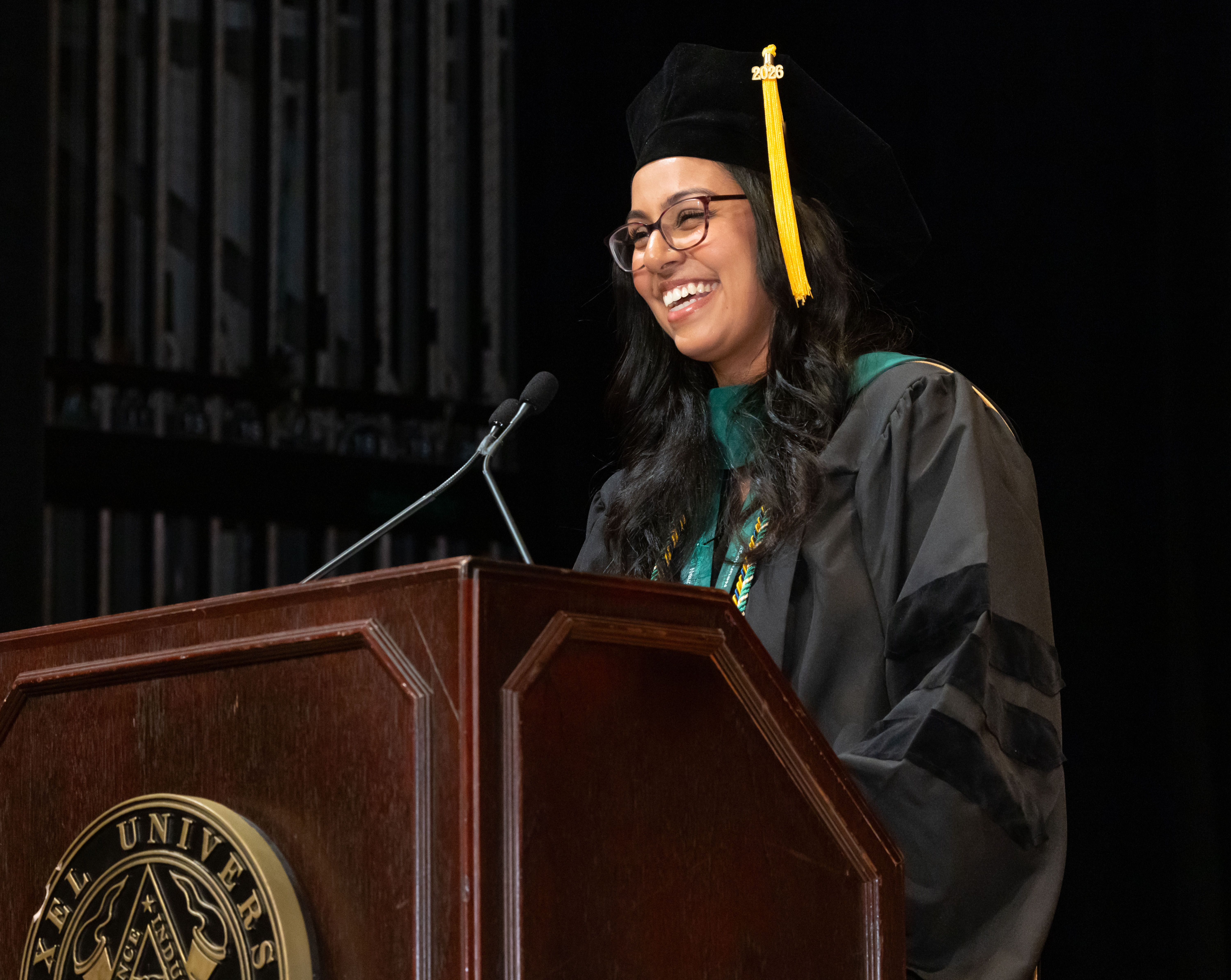 student speaker stands at podium and smiles