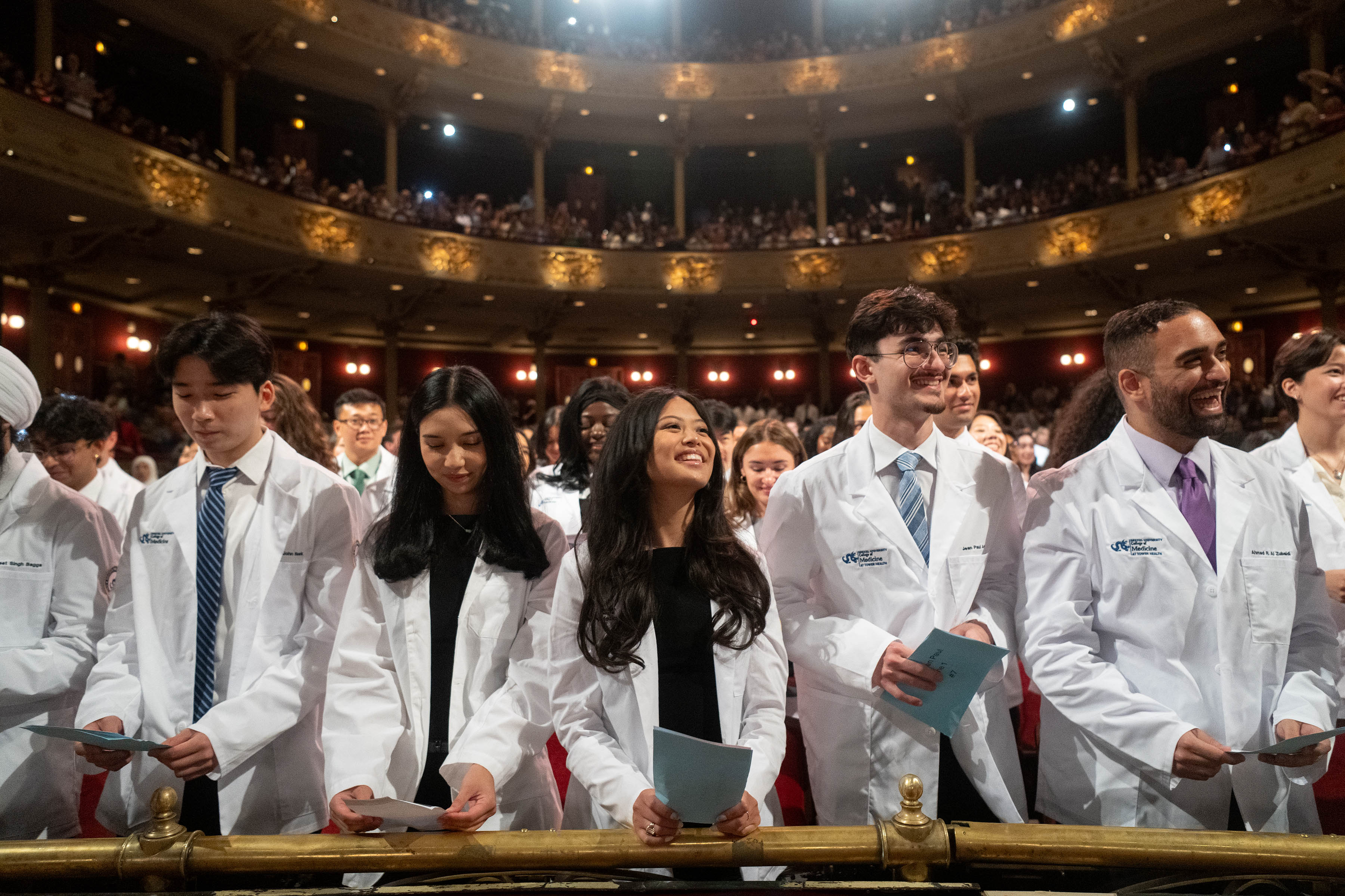 Students holding event pamphlet and smiling after completing oath