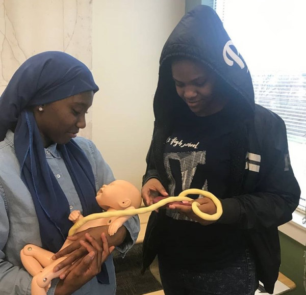 Deonna Hammonds (left) and Ajanai Stinson-Downing hold the simulated baby they saw being 'born'