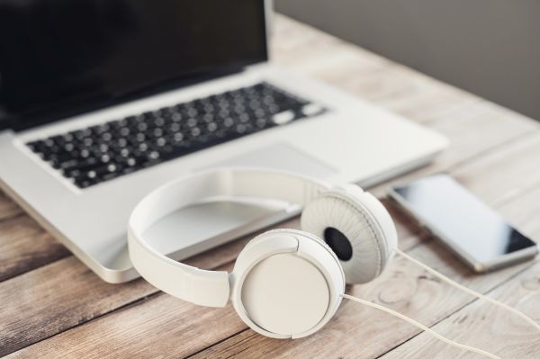 A laptop keyboard and phone with headphones