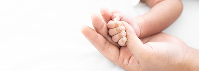 Newborn baby holding mother's finger.