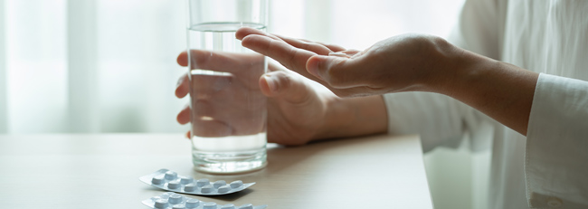 Holding medicine with a glass of water.
