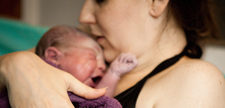 Mother holding newborn in birthing tub after home water birth.