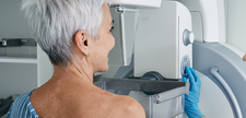 Senior woman having mammography scan at hospital with medical technician.
