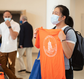 A student at orientation receives a T-shirt indicating which Learning Society she belongs to.