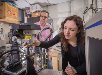 Patrick Loll looks on as Emily Arturo adjusts the X-ray diffraction equipment. The crystal is placed into the high-intensity beam, and the diffraction pattern is recorded by the detector at right.
