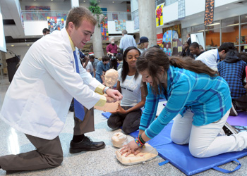 A Drexel medical student/resident at an AHA CPR event demonstrating CPR to kids.