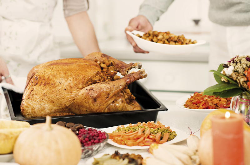 A turkey, carrots, cranberries and other side dishes are placed on a table for a holiday meal.