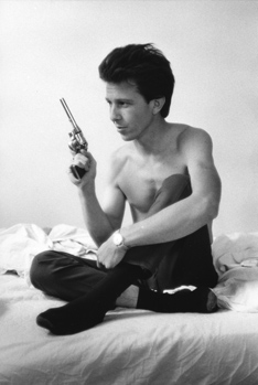 A shirtless man holding a revolver.