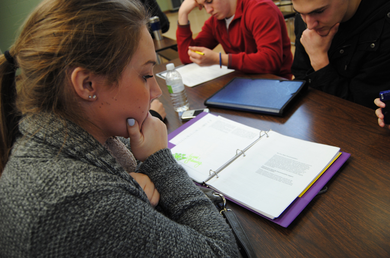 Students studying from binders at a table.