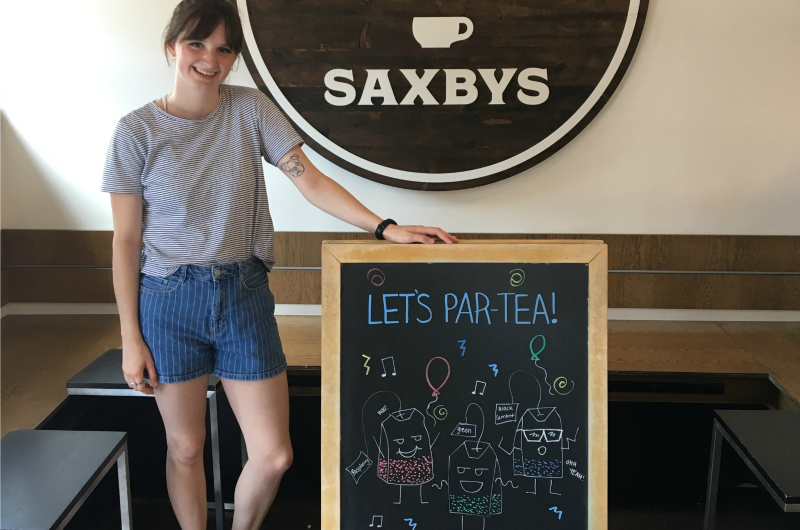 Graphic design major Abbey Nesbitt poses with one of the Saxbys chalkboard signs displaying her art.