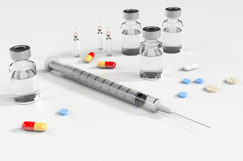 A syringe, pills and bottles of prescriptions