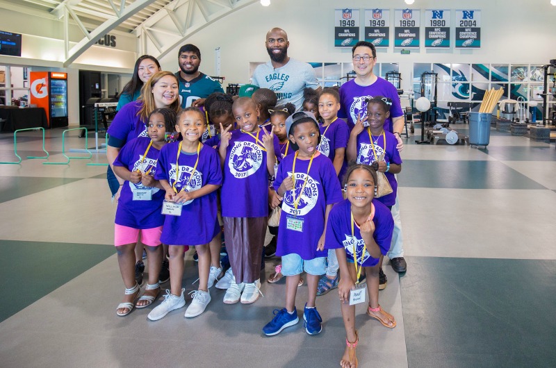 ExCITe Center Director Youngmoo Kim, Eagles safety Malcolm Jenkins and a group of Young Dragons pose in the team's weight room.